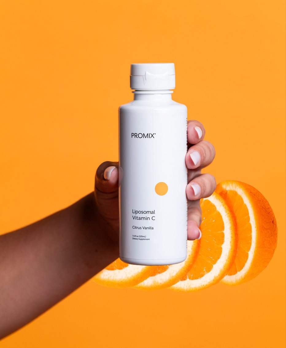 Promix Liposomal Vitamin C bottle held in hand with orange slices