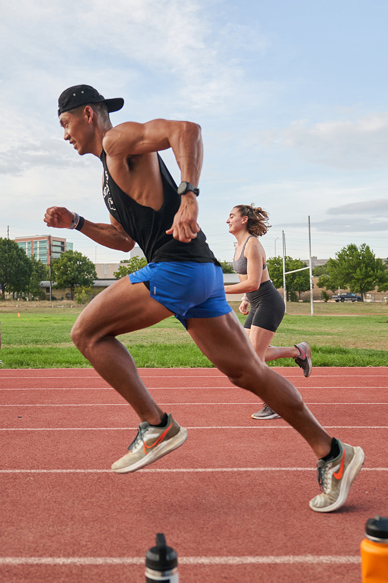 A runner mid stride on an outdoor running track.