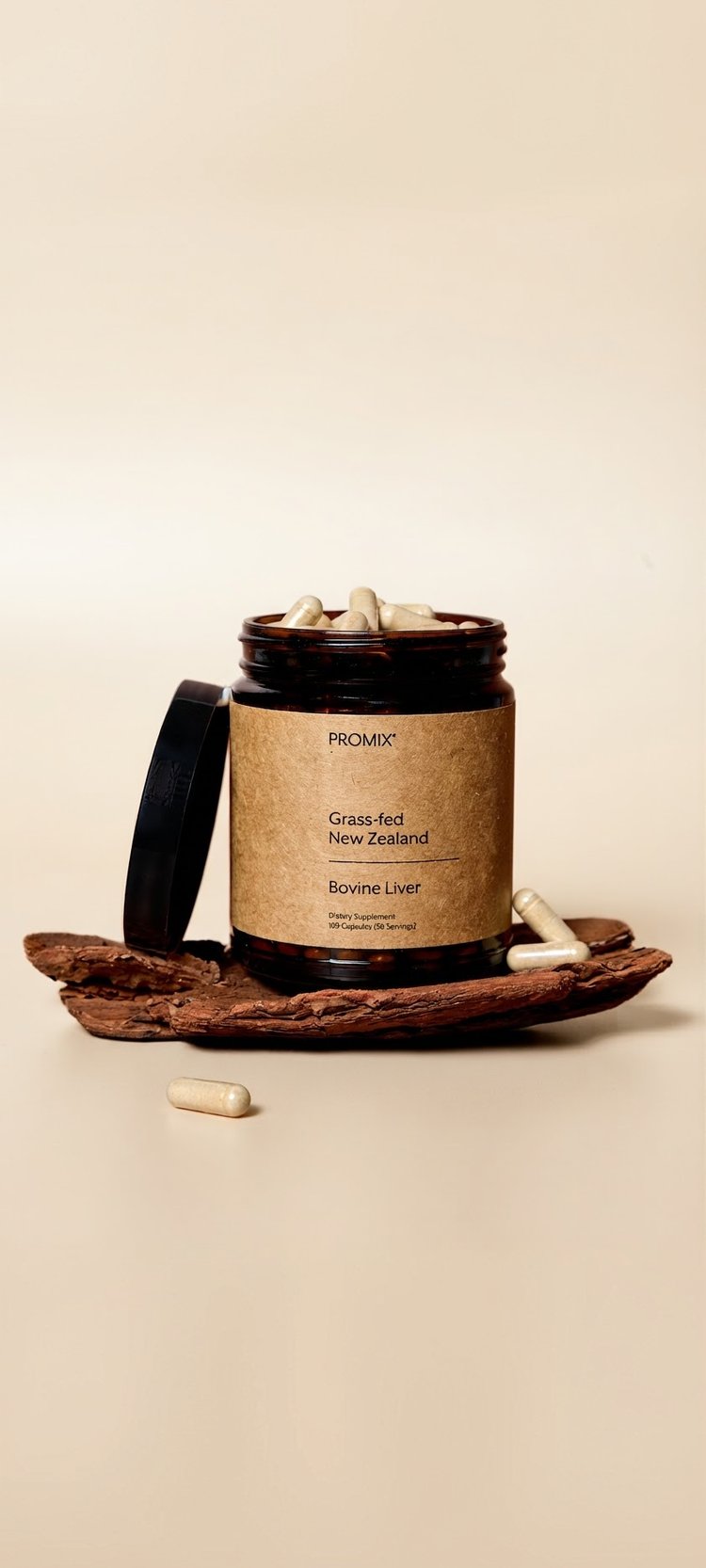 A jar of Promix Raw Liver Capsules on a piece of bark, with capsules around it